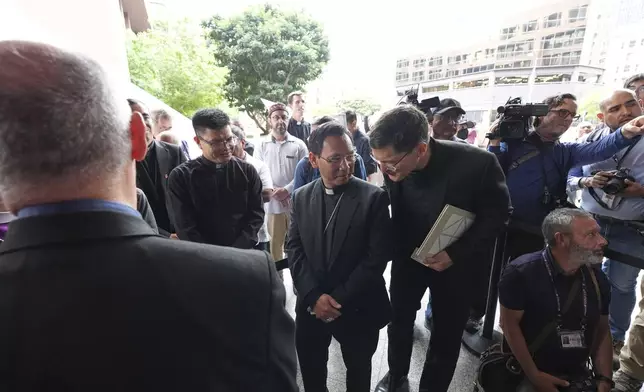 Bishop Michael Pham, center, speaks with Pastor Scott Santa Rosa, right, as an inter-faith group gets ready to enter a federal building to be present during immigration hearings Friday, June 20, 2025, in San Diego. (AP Photo/Gregory Bull)