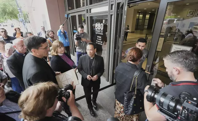 Bishop Micheal Pham, center, leads an inter-faith group as they enter a federal building to be present during immigration hearings, Friday, June 20, 2025, in San Diego. (AP Photo/Gregory Bull)