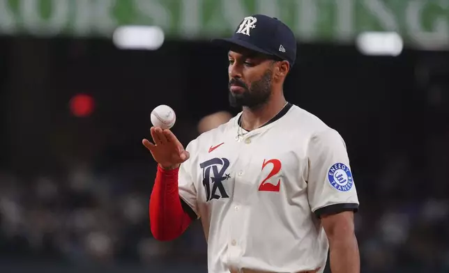 Texas Rangers second baseman Marcus Semien looks at the ball as a play is being reviewed during the third inning of a baseball game against the Chicago White Sox, Friday, June 13, 2025, in Arlington, Texas. (AP Photo/LM Otero)