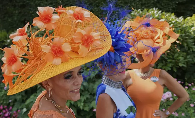 Racegoers pose for photographs wearing colorful hats on the first day of the Royal Ascot horse race meeting at Ascot, England, Tuesday, June 17, 2025. (AP Photo/Alberto Pezzali)