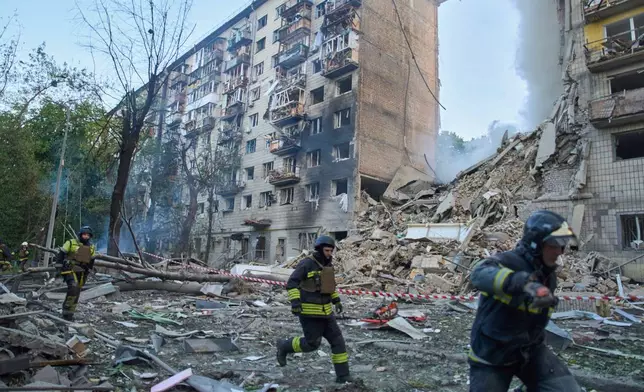 Rescuers run to a shelter to hide from an air raid during a Russian missile and drone barrage in Kyiv, Ukraine, Tuesday, June 17, 2025. (AP Photo/Efrem Lukatsky)