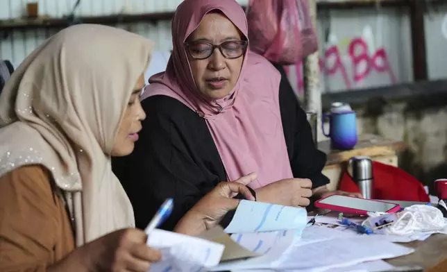 Nina Herlina reviews her trading record ahead of of the Eid al-Adha festival, at her livestock stall in Jakarta, Indonesia, Wednesday, June 4, 2025.(AP Photo/Achmad Ibrahim)