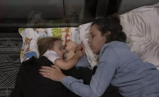 ADDS NAMES: Tehila Alush, and her daughter Ariel Asraf, 3, take shelter in an underground metro station as a precaution against possible Iran missile attacks, in Ramat Gan, near Tel Aviv, Israel, Tuesday, June 17, 2025. (AP Photo/Oded Balilty)