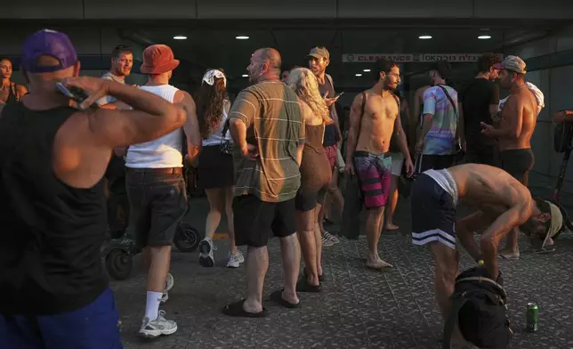 Beachgoers take shelter at the entrance of a garage during a missile alert from Iran, in Tel Aviv, Israel, Wednesday, June 18, 2025. (AP Photo/Ohad Zwigenberg)