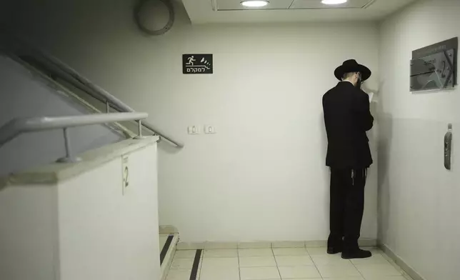 A Jewish man prays as he takes shelter during sirens warning of incoming fire at Israel's Magen David Adom emergency service during a blood drive to prepare for mass casualties in the event of strikes by Iran, in Jerusalem, Saturday, June 14, 2025. (AP Photo/Maya Alleruzzo)