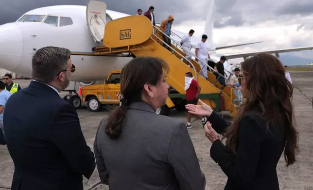 U.S. Homeland Security Secretary Kristi Noem, right, talks to ERO Regional Attaché Guadalupe "Lupita" Serna and U.S. Ambassador to Guatemala Tobin Bradley as they watch people deported from the United States disembark a repatriation flight, at La Aurora International Airport in Guatemala City, Thursday, June 26, 2025. (Anna Moneymaker/Pool Photo via AP)