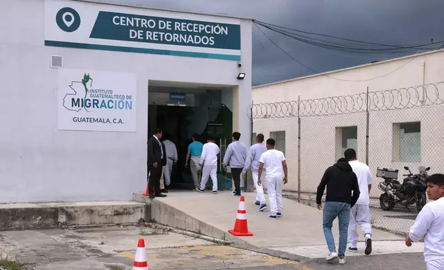 People deported from the United States walk into a processing center after arriving on a repatriation flight, during a Department of Homeland Security operations tour for visiting Homeland Security Secretary Kristi Noem, at La Aurora International Airport in Guatemala City, Thursday, June 26, 2025. (Anna Moneymaker/Pool Photo via AP)