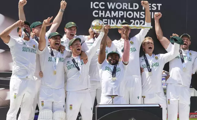 South Africa's captain Temba Bavuma holds the winner's trophy and celebrates with teammates on the podium after their win in the World Test Championship final against Australia at Lord's cricket ground in London, Saturday, June 14, 2025. (AP Photo/Kirsty Wigglesworth)