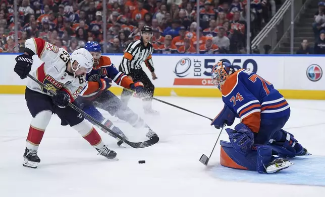 Florida Panthers' Brad Marchand (63) scores the winning goal against Edmonton Oilers goalie Stuart Skinner (74) as Leon Draisaitl (29) watches during the second overtime period in Game 2 of the NHL Stanley Cup Final in Edmonton, Alberta, Friday, June 6, 2025. (Darryl Dyck/The Canadian Press via AP)