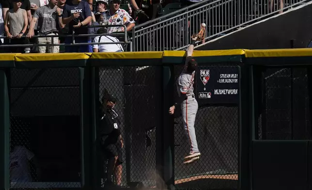 San Francisco Giants right fielder Mike Yastrzemski (5) jumps but can't catch a home run ball from Chicago White Sox's Andrew Benintendi during the sixth inning of a baseball game Saturday, June 28, 2025, in Chicago. (AP Photo/Erin Hooley)