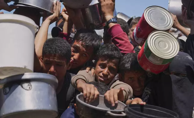 Palestinians struggle to get donated food at a community kitchen in Khan Younis, southern Gaza Strip, Monday, June 2, 2025. (AP Photo/Abdel Kareem Hana)