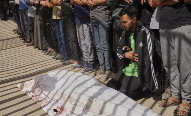 Mourners pray beside the body of Adnan Abu Harb who was killed while heading to a Gaza aid hub, during his funeral at the Nasser Hospital in Khan Younis, southern Gaza Strip, Tuesday, June 3, 2025. (AP Photo/Abdel Kareem Hana)