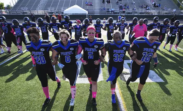 Detroit Prowl's Toya Shinaul, from left to right, Kelly Bernadyn, Sydney Hebel, Jasmine Hamilton and Allie Gorcyca walk out for the coin toss at the start of an AWFL women's football game against the Lansing Legacy, in Allen Park, Mich., Saturday, May 10, 2025. (AP Photo/Paul Sancya)