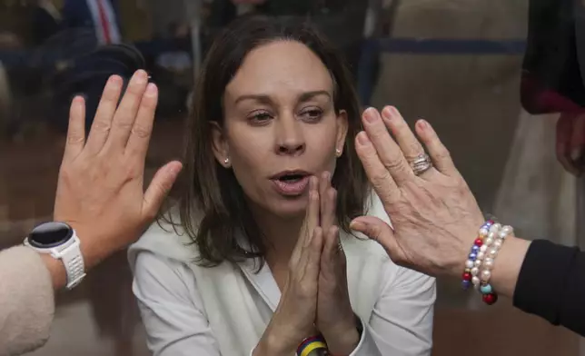Maria Claudia Tarazona, the wife of Colombian Sen. Miguel Uribe Turbay, interacts with supporters through a glass from inside the clinic where her husband is being treated after being shot at a political rally in Bogota, Colombia, Wednesday, June 11, 2025. (AP Photo/Ramon Espinosa)