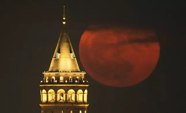A full moon rises behind Galata Tower landmark in Istanbul, Turkey, Wednesday, June 11, 2025. (AP Photo/Emrah Gurel)