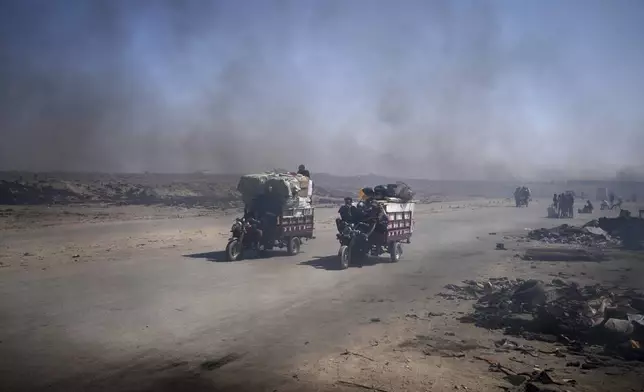 Residents ride through black smoke coming from makeshift burners used to extract fuel from melted plastic, along the Sea Road, south of Gaza City, Sunday, June 22, 2025. (AP Photo/Abdel Kareem Hana)