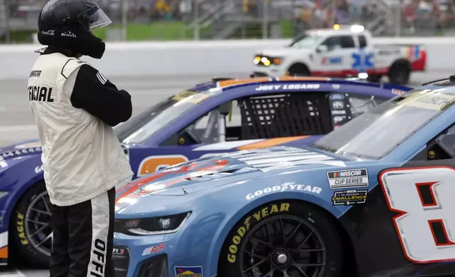 An official stands as cars are parked during a red flag weather delay during a NASCAR Cup Series auto race, Saturday, June 28, 2025, in Hampton, Ga. (AP Photo/Butch Dill)