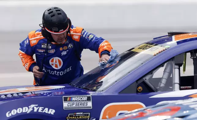 A crew member for driver Joey Logano wipes off water from the windshield during a red flag weather delay in a NASCAR Cup Series auto race, Saturday, June 28, 2025, in Hampton, Ga. (AP Photo/Butch Dill)
