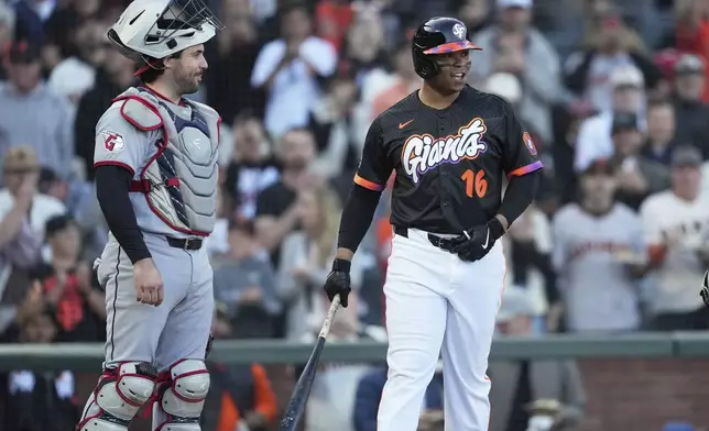 San Francisco Giants' Rafael Devers (16) smiles as he walks to the plate next to Cleveland Guardians catcher Austin Hedges during the first inning of a baseball game in San Francisco, Tuesday, June 17, 2025. (AP Photo/Jeff Chiu)