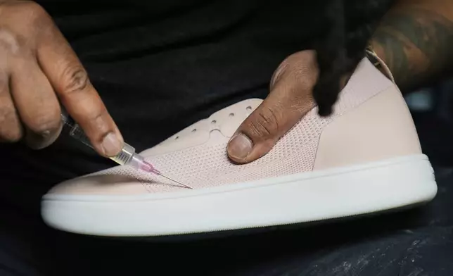 Gary Brown, assembly technician at Made Plus, cleans a pair of sneakers to be prepared for shipment at the company's manufacturing facility in Annapolis, Md., Tuesday, June 10, 2025. (AP Photo/Stephanie Scarbrough)