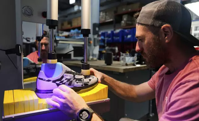 Andrew McLean, assembly technician at Made Plus, performs visual checks on a shoe before bonding the outsole to the upper at the company's manufacturing facility in Annapolis, Md., Tuesday, June 10, 2025. (AP Photo/Stephanie Scarbrough)