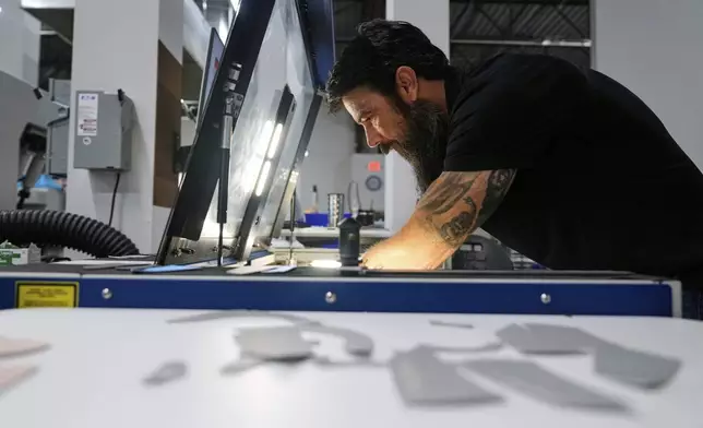 Craig Simile, senior operations manager at Made Plus, prepares materials with a laser cutting machine at the company's manufacturing facility in Annapolis, Md., Tuesday, June 10, 2025. (AP Photo/Stephanie Scarbrough)