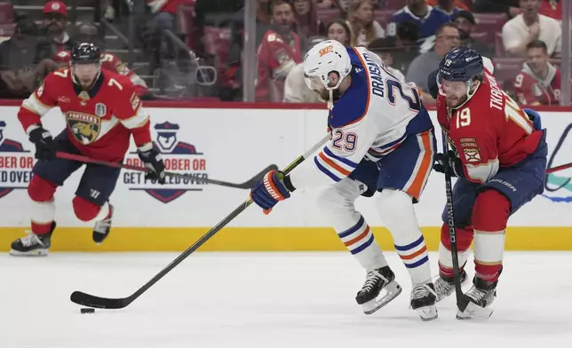 Edmonton Oilers center Leon Draisaitl (29) takes control of the puck as Florida Panthers left wing Matthew Tkachuk (19) defends during the third period of Game 4 of the NHL hockey Stanley Cup Final Thursday, June 12, 2025, in Sunrise, Fla. (AP Photo/Lynne Sladky)