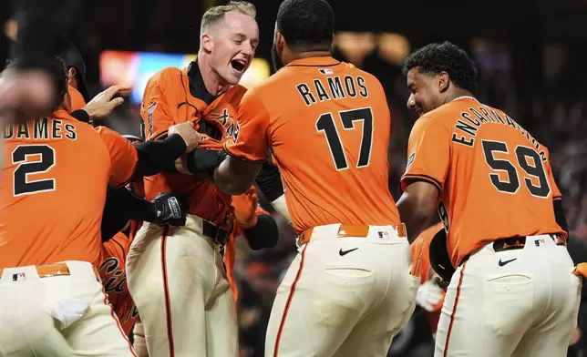 San Francisco Giants' Tyler Fitzgerald, center left, is mobbed by teammates after scoring the game-winning run on a wild pitch thrown by Atlanta Braves pitcher Pierce Johnson during the 10th inning of a baseball game Friday, June 6, 2025, in San Francisco. (AP Photo/Godofredo A. Vásquez)
