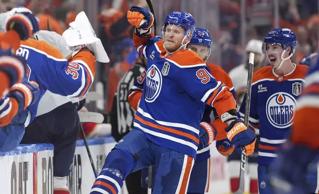 Edmonton Oilers' Corey Perry (90) and Ryan Nugent-Hopkins, back right, celebrate Perry's tying goal against the Florida Panthers during the third period in Game 2 of the NHL Stanley Cup Final, in Edmonton, on Friday, June 6, 2025. (Darryl Dyck/The Canadian Press via AP)