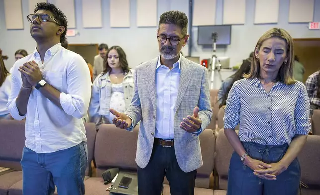 José Luis Orozco, a pastor from Nicaragua, prays with his son, Josias, 17, left, and wife, Ruth, before speaking to members of the Oasis Church, in Taylor, Texas, June 15, 2025. (AP Photo/Rodolfo Gonzalez)