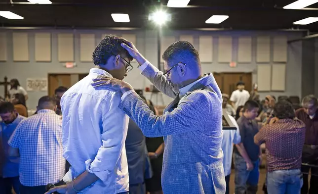 José Luis Orozco, a pastor from Nicaragua, places his hand on his son, Josias, 17, as he prays for him and the congregation of the Oasis Church, in Taylor, Texas, June 15, 2025. (AP Photo/Rodolfo Gonzalez)