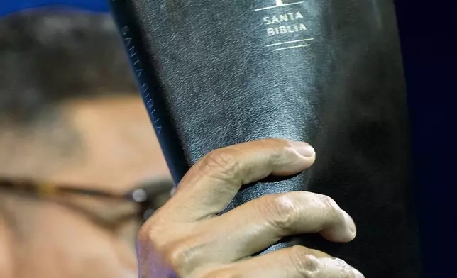 José Luis Orozco, a pastor from Nicaragua, holds up his bible as he ministers to members of the Oasis Church, in Taylor, Texas, June 15, 2025. (AP Photo/Rodolfo Gonzalez)