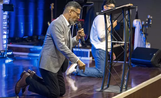 José Luis Orozco, a pastor from Nicaragua, kneels on stage as he ministers to members of the Oasis Church, in Taylor, Texas, June 15, 2025. (AP Photo/Rodolfo Gonzalez)