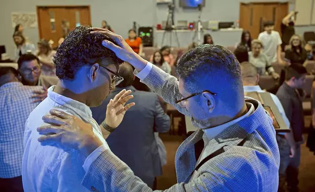 José Luis Orozco, a pastor from Nicaragua, places his hand on his son, Josias, 17, as he prays for him and the congregation of the Oasis Church, in Taylor, Texas, June 15, 2025. (AP Photo/Rodolfo Gonzalez)