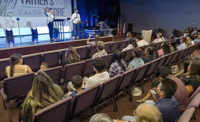 José Luis Orozco, a pastor from Nicaragua, left, flanked by his son, Josias, 17, translating, ministers to members of the Oasis Church, in Taylor, Texas, June 15, 2025. (AP Photo/Rodolfo Gonzalez)