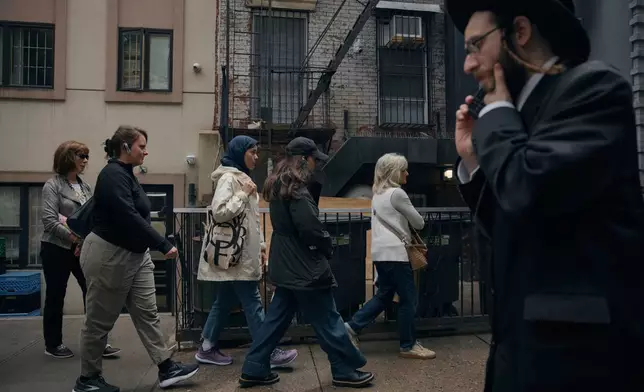 Tour participants walk past an ultra-Orthodox Jewish man during a tour by Frieda Vizel of the Hasidic section of Williamsburg in the Brooklyn borough of New York on Monday, June 16, 2025. (AP Photo/Andres Kudacki)