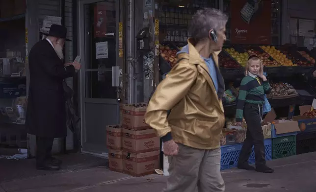 A tourist passes ultra-Orthodox Jews during a guided walk through the Hasidic section of Williamsburg in the Brooklyn borough of New York on Monday, June 16, 2025. (AP Photo/Andres Kudacki)