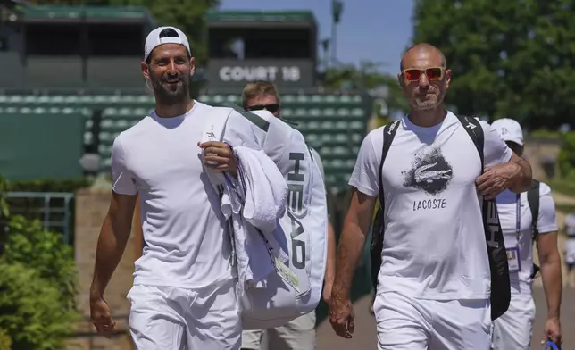 Novak Djokovic of Serbia, left, attends a practice session ahead of the Wimbledon tennis Championships in London, Friday, June 27, 2025. (AP Photo/Kin Cheung)