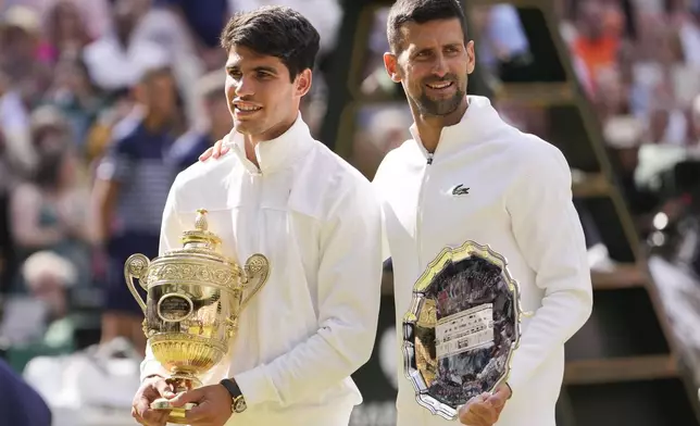 FILE - Carlos Alcaraz of Spain holds his trophy as he stands with Novak Djokovic of Serbia after winning the men's singles final at the Wimbledon tennis championships in London, Sunday, July 14, 2024. (AP Photo/Alberto Pezzali,File)