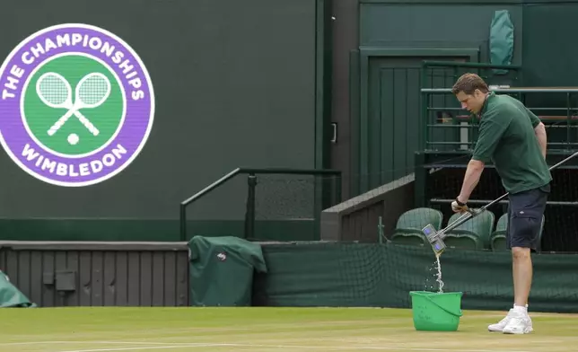 FILE - In this July 13, 2017, file photo, Ben Sidgwick wrings out his mop on Center Court at the All England Club at the Wimbledon Tennis Championships in London. (AP Photo/Alastair Grant, File)