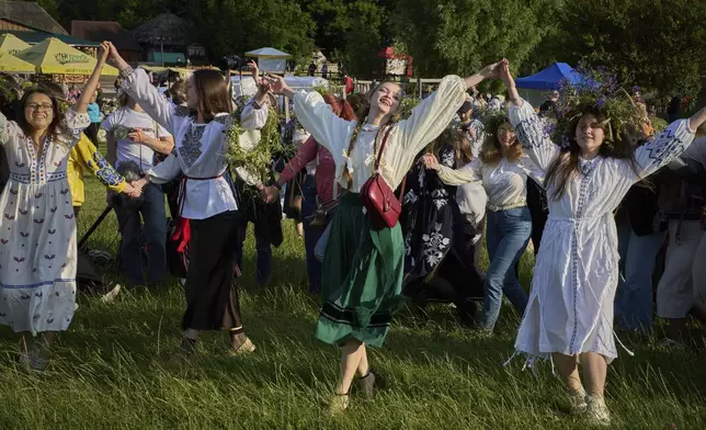 People wearing traditional Ukrainian clothing dance in circle during a traditional midsummer celebration in Pyrohiv, Ukraine, outside of Kyiv, Saturday, June 21, 2025. (AP Photo/Efrem Lukatsky)