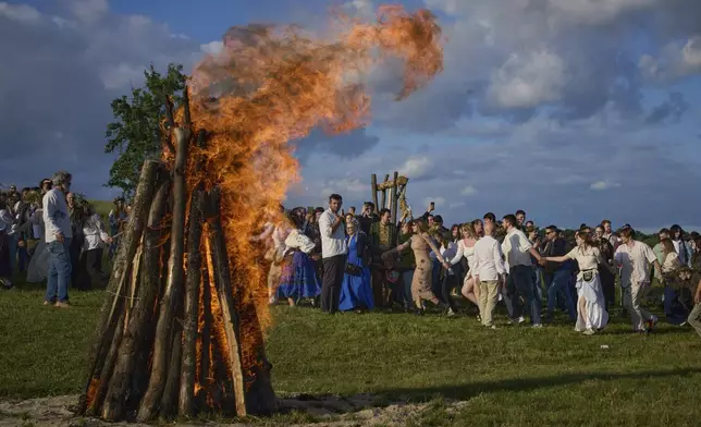 People dance in circle around a bonfire during a traditional midsummer celebration in Pyrohiv, Ukraine, outside of Kyiv, Saturday, June 21, 2025. (AP Photo/Efrem Lukatsky)