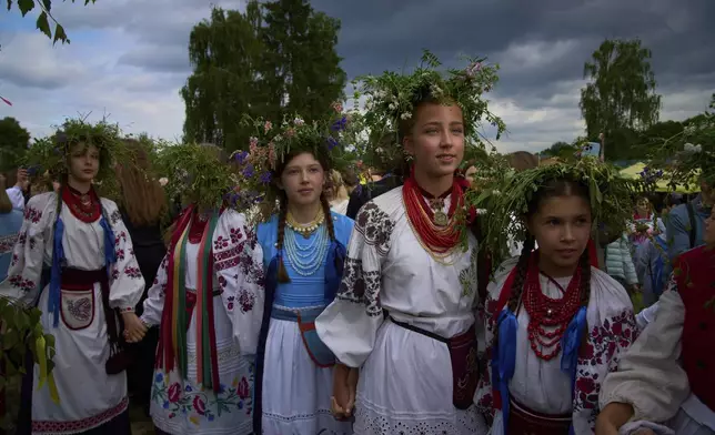 Young women dressed in traditional Ukrainian clothing dance in circle during a traditional midsummer celebration in Pyrohiv, Ukraine, outside of Kyiv, Saturday, June 21, 2025. (AP Photo/Efrem Lukatsky)