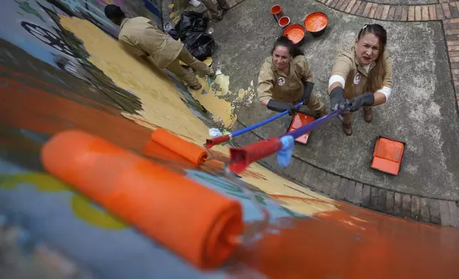 Inmates work on the recovery of a park as part of a new program helping prisoners reduce their sentences in Bogota, Colombia, Thursday, June 5, 2025. (AP Photo/Fernando Vergara)