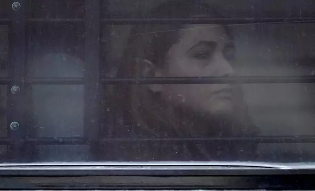 A woman sits on a bus behind barred and tinted windows after she was arrested following an appearance at immigration court, Thursday, June 5, 2025, in San Antonio. (AP Photo/Eric Gay)