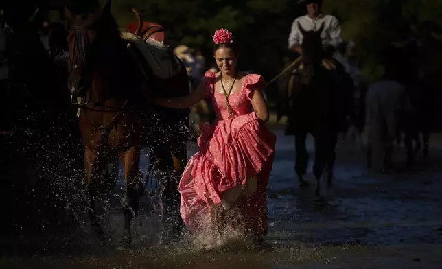 Worshippers cross the Quema River on their way to the shrine of El Rocio near Aznalcázar, Spain, on Thursday June 5, 2025, during the annual pilgrimage in which hundreds of thousands of devotees of the Virgin del Rocio converge in and around the shrine. (AP Photo/Emilio Morenatti)