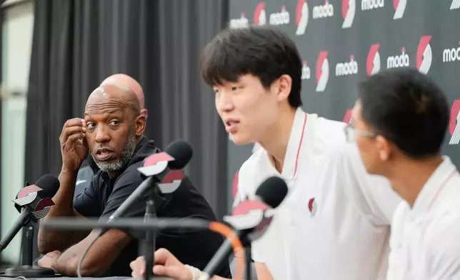 Portland Trail Blazers head coach Chauncey Billups, left, listens as Portland Trail Blazers' Yang Hansen, of China, speaks during an NBA basketball press conference, Friday, June 27, 2025, in Portland, Ore. (AP Photo/Jenny Kane)