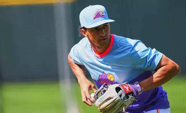 Colorado Rockies shortstop Ryan Ritter warms up before making his Major League debut in a baseball game against the New York Mets, Friday, June 6, 2025, in Denver. (AP Photo/David Zalubowski)