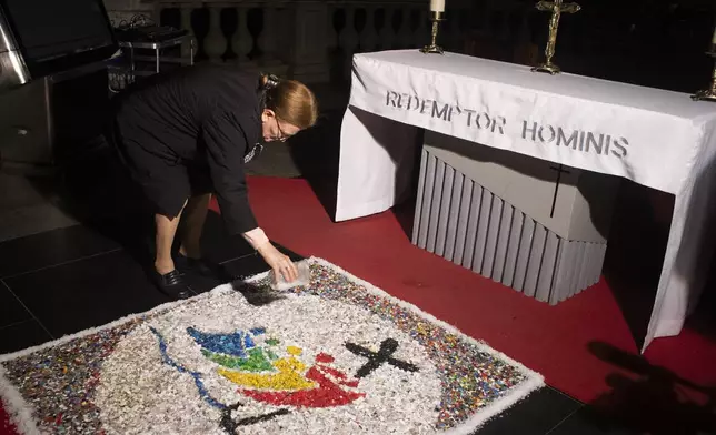 A woman puts the last touches on a rug made from plastic bottle caps for a Mass celebrating the Catholic holiday of Corpus Christi near the Christ the Redeemer statue in Rio de Janeiro, Thursday, June 19, 2025 (AP Photo/Bruna Prado)