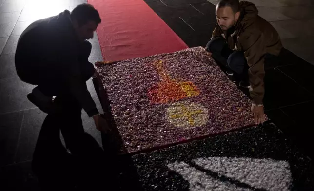People place rugs made from plastic bottle caps for a Mass celebrating the Catholic holiday of Corpus Christi near the Christ the Redeemer statue in Rio de Janeiro, Thursday, June 19, 2025 (AP Photo/Bruna Prado)